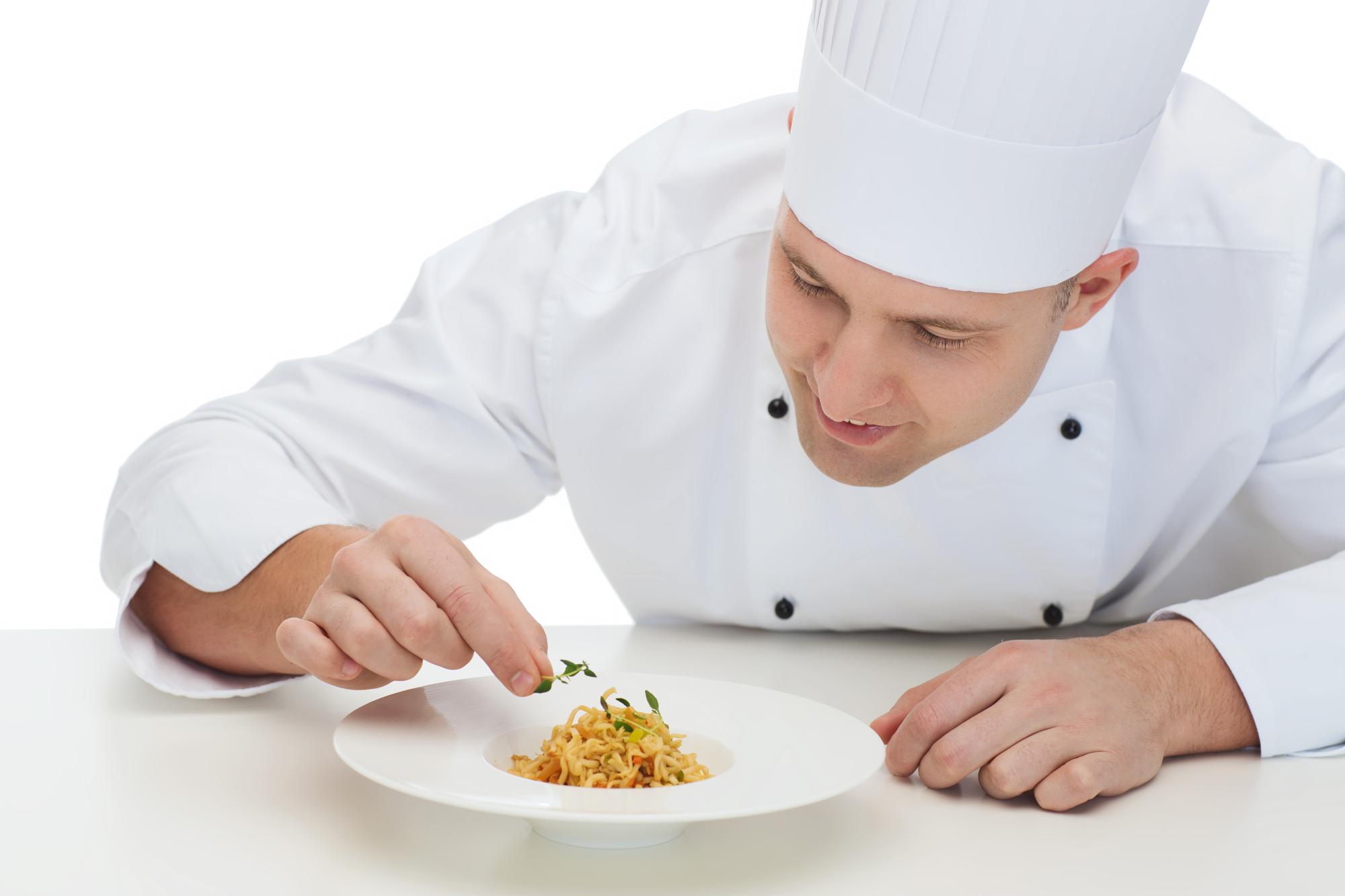Student plating a dish under instructor guidance